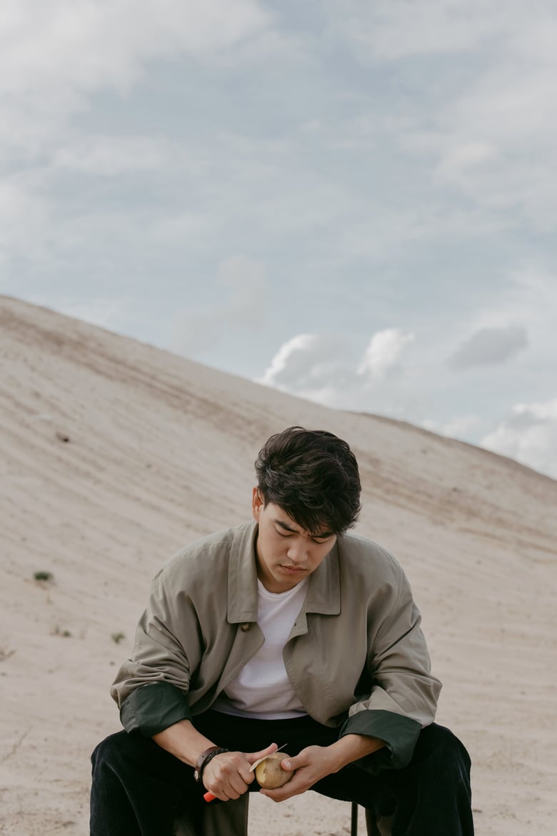 A Man Sitting while Peeling a Potato